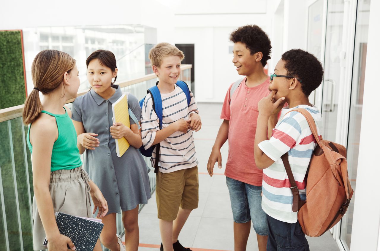 Illustratieve foto van een groep leerlingen die in een schoolgang met elkaar praten en lachen, zonder telefoons